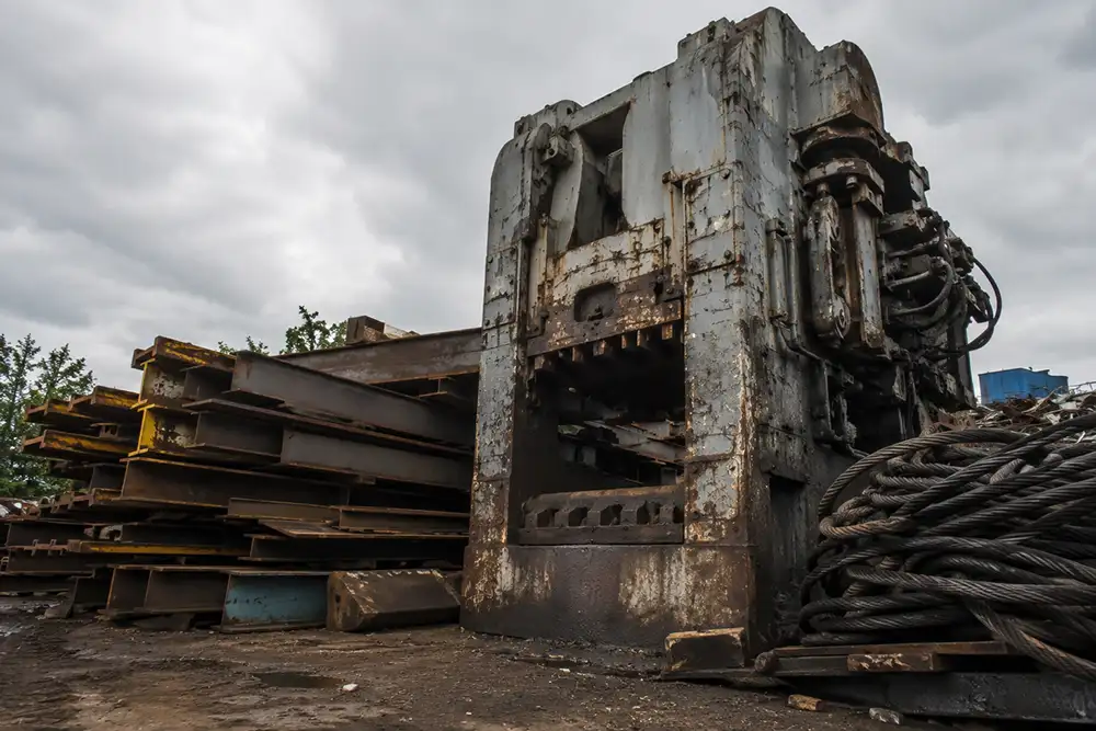 Heavy industrial scrap at Thornton Iron & Metal in Town Creek: a dismantled steel press, structural beams, plate steel, and heavy cable